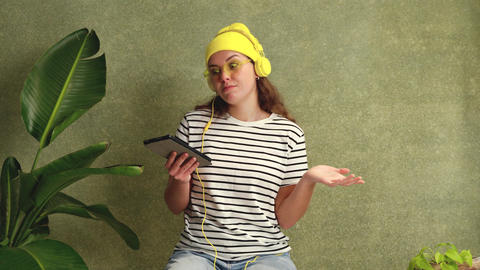 Young Woman with Tablet and Headphones Making a Doubtful Gesture