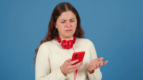 Confused Young Woman with Red Headphones Gesturing in Frustration