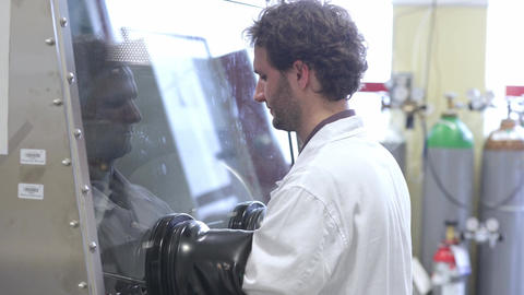 Laboratory technician doing dangerous experiment with protective special box and