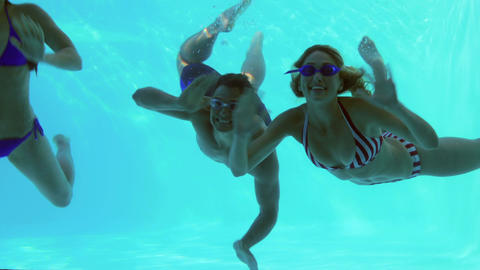 Three friends diving into swimming pool and waving