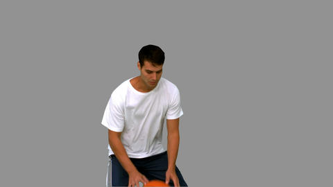 Handsome man playing with a basketball on grey screen