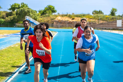 Young athletes running on blue track during competition