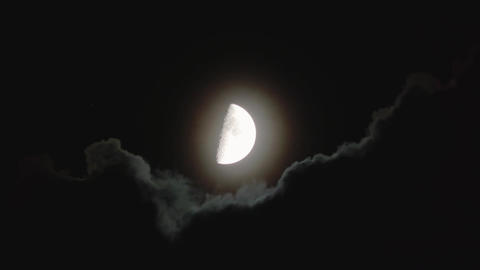 Moon covered by clouds in dark night sky. Skyscape with flying black cloud