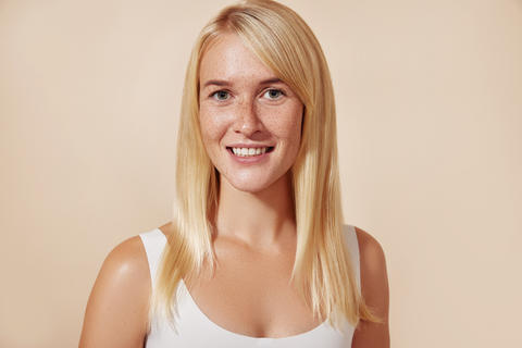 Portrait of a beautiful woman with freckles in studio. Young female with perfect skin against a