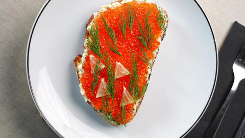 Gourmet appetizer featuring crispy toast topped with creamy cheese, bright red caviar, fresh dill