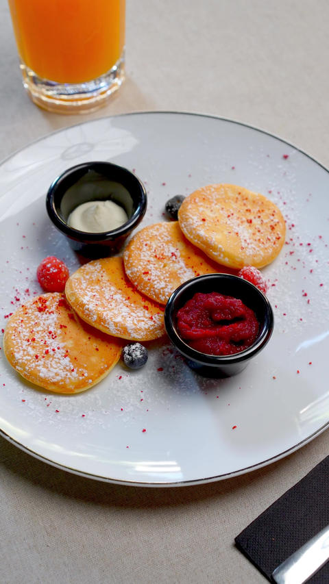 Ukrainian cottage cheese pancakes garnishing wooden board, surrounded by fresh strawberries, sour