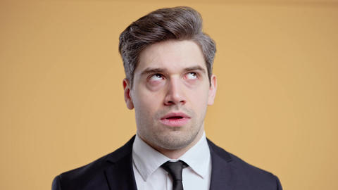 Irritated handsome businessman sighs, rolling eyes on yellow. Hide