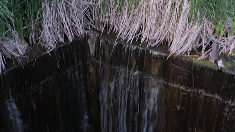 Water pours and falls into a hole with concrete walls - a hydrological structure on a dam