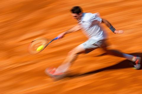 Tennis player making a powerful forehand shot on orange clay cou