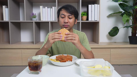 A man is eating a burger and drinking a soda