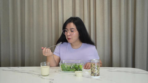 A woman is eating a salad with a fork