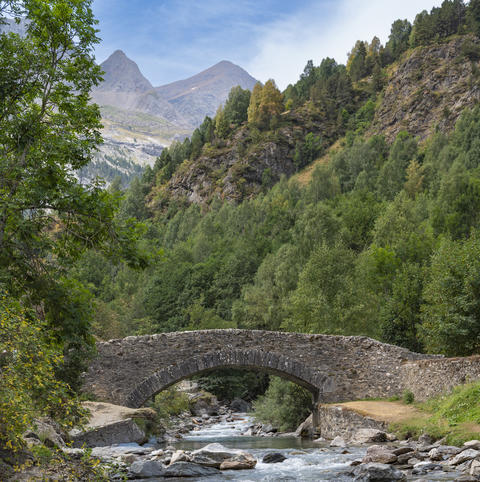 Scenic view of Pyrenees stone bridge over Gavarnie stream at dawn, surrounded by