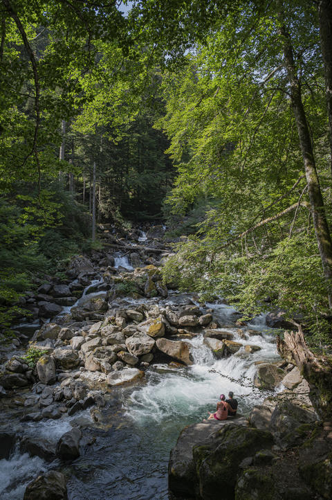 Couple seated by a cascading stream in the Pyrenees at Cauterets by Pont d
