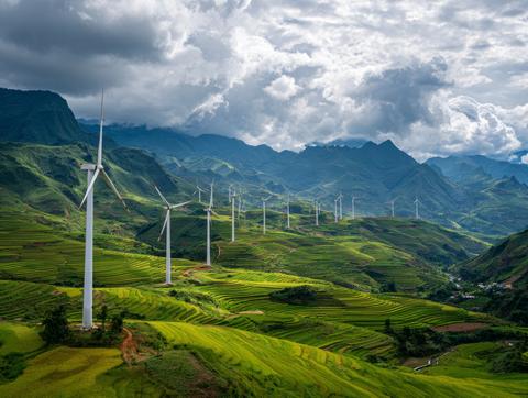 Wind turbines across terraced green fields and mountains