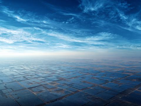 Solar farm beneath blue sky with wispy clouds