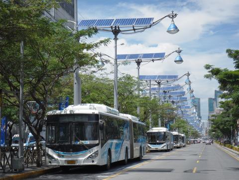 City street with solar powered streetlights and buses