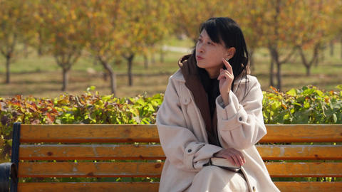 Woman in Cozy Coat Reading on Park Bench in Autumn