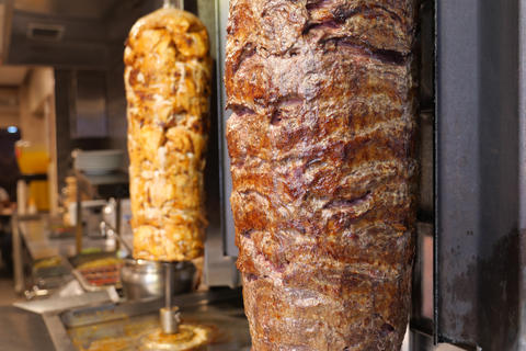 Doner Kebab Spit Roast on Vertical Rotating Grill In Busy Kitchen Setting