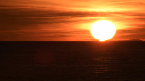 Sun hidding in the horizon line at sunset in the beach