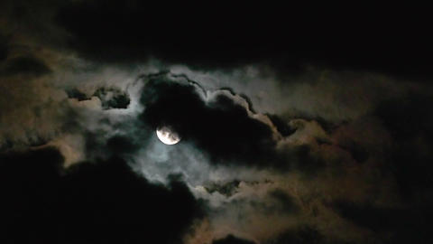 Moon in the clouds. Mystery of the night sky. Clouds fly in front of the moon. Mysterious night