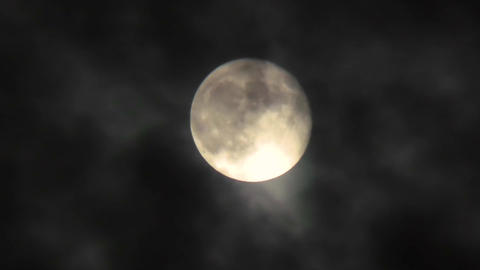 Clouds fly in front of the moon in the night sky. Full moon close-up and cloudy dark sky