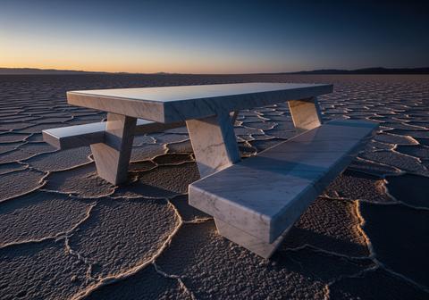 Minimalist white marble picnic table isolated on a vast cracked salt flat desert at sunset