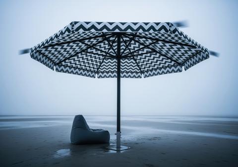 Oversized black and white chevron umbrella and bean bag on a misty beach shore