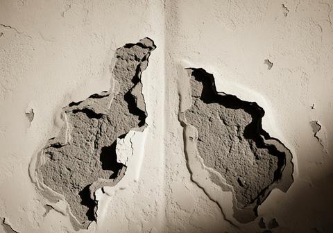 Sepia toned abstract texture of a crumbling stucco wall with peeling paint and decay