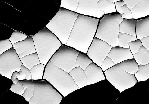 Abstract geometric pattern of cracked white paint on a stark black surface