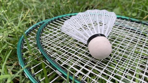 Badminton rackets and shuttlecock against a background of green grass