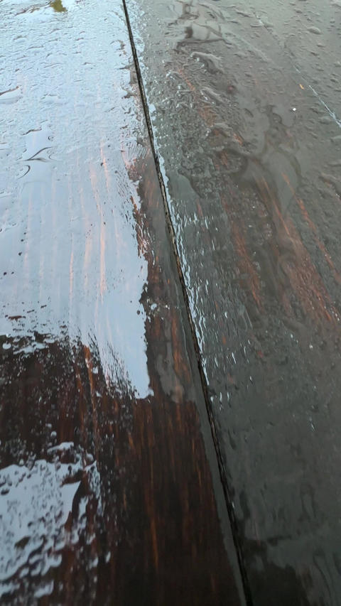 A closeup of a wet bench in the rain
