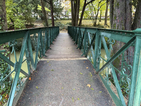Old-fashioned wooden and iron pedestrian bridge with decorative railings over