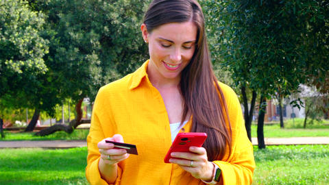 Young woman shopping online with credit card and smartphone outdoors