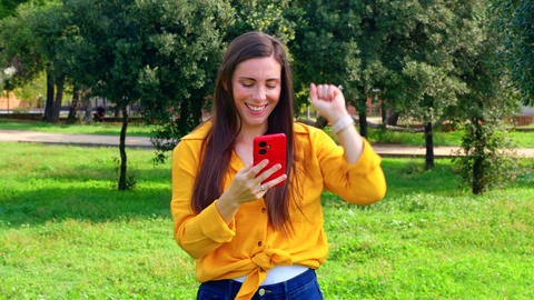 Excited woman celebrating online game bet win holding smartphone outdoors