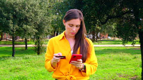 Young woman shopping online with credit card and smartphone outdoors