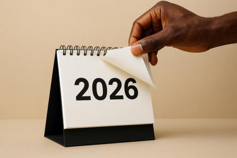 Black hand turns page on desk calendar displaying 2026 year