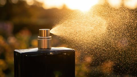 Black Perfume Bottle Spraying Mist Golden Hour Sun Flare