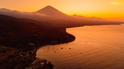 Drone view scenic panorama of coastline with silhouette of volcano and sunset with ocean in Bali