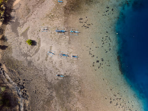 Boats in harbor with blue ocean in Bali. Aerial view