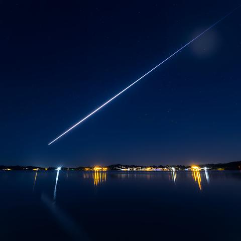 Meteor streaks across night sky over tranquil lake night sky night sky astronomy galaxy nature space