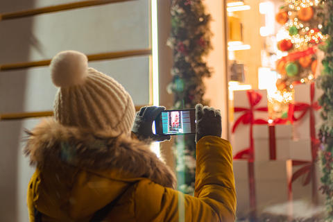 Woman tourist takes photographs of festive city decor on her smartphone