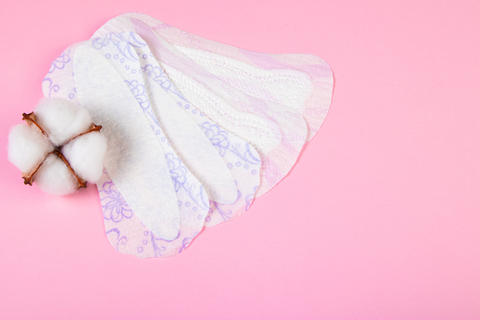 Sanitary pad and cotton flower on pink background. Daily feminine hygiene product