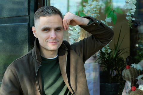 Man sitting casually with a thoughtful expression in an urban cafe setting