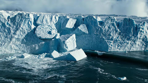 Massive glacier calving and melting ice chunks falling into the cold ocean. Concept of global