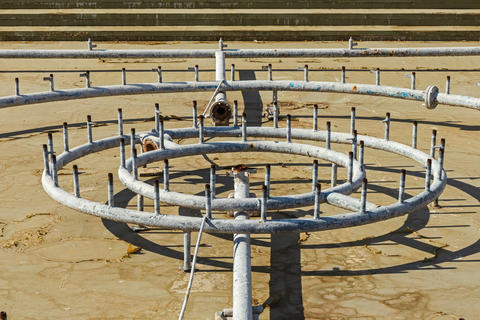 Old city fountain without water with rusty metal pipes