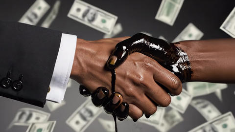 Adult businessmen shaking hands, one covered in dripping oil, with money falling around. Concept of