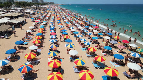 Vibrant crowded beach with adults and children relaxing, swimming, and sunbathing under colorful