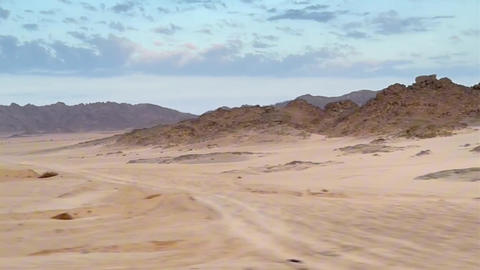 Travel scene featuring motion blurred vehicle view over vast rocky desert landscape in