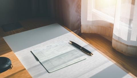 An image of keeping a household account book at a bright table by the window. Bankbook