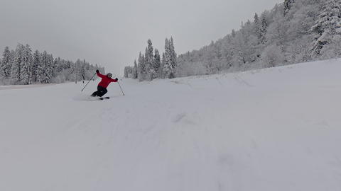 Person skiing down empty snowy mountain slope, winter landscape view